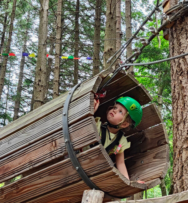 Une fillette traverse un tunnel dans le cadre d'un parcours d'accrobranche.