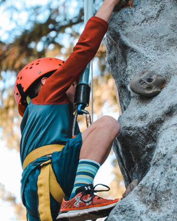 Une enfant est entrain d'escalader une parois rocheuse