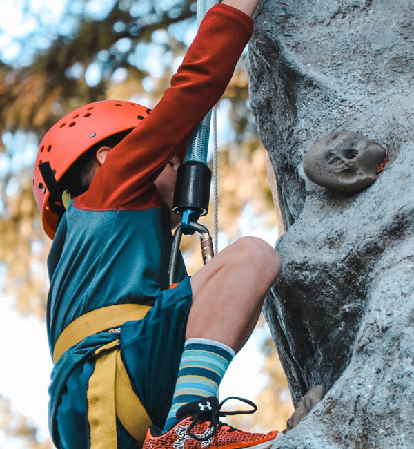 Une enfant est entrain d'escalader une parois rocheuse