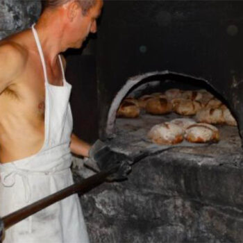 Un villageois sort les miches de pain du four.