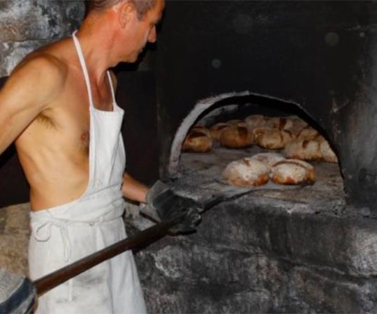 Un villageois sort les miches de pain du four.